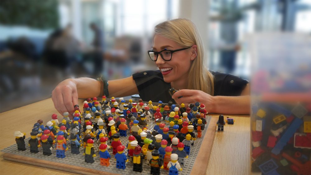 Blije deelnemer die LEGO® minifiguren uitzoekt