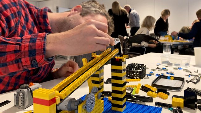 Een deelnemer die bouwt aan een knikkerbaan van LEGO® bouwstenen