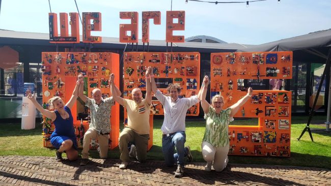 Het eindresultaat van het evenement met LEGO® bouwstenen: de gigantische letters die samen "we are OPS" (operations) vormen. Met daarvoor het team van THE POWER OF BRICKS: Marian, Martin, Ernesto, Marcel en Bibi